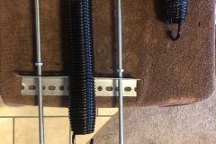 The spring fits onto the backets. The nuts get screwed down the threaded bolt to push the backet out, stretching the spring.